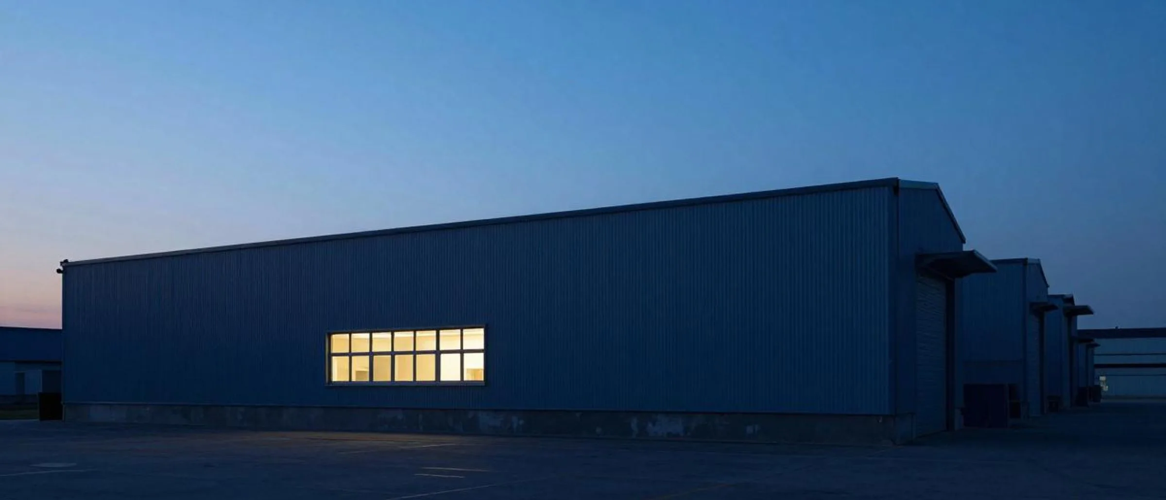 Industriegebäude in der Dämmerung, ein einzelnes Fenster leuchtet